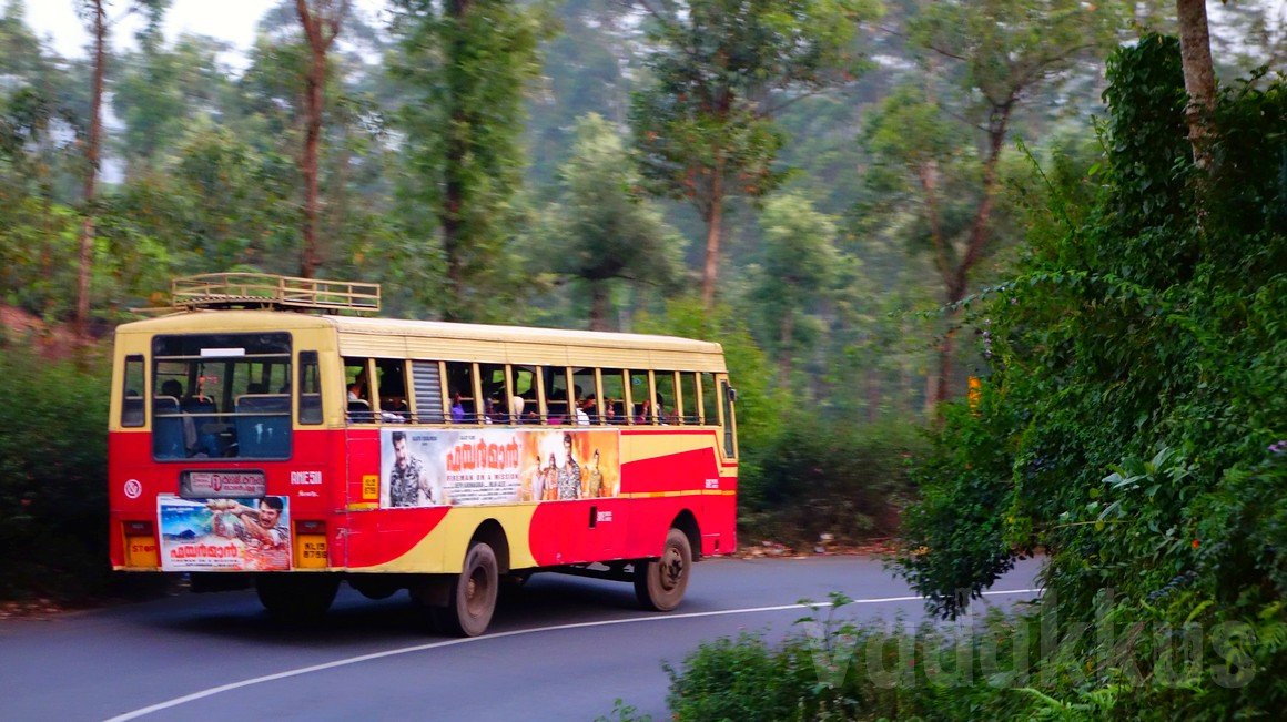 A KSRTC fast passenger bus rounds a corner at high speed on KK Road near Kumily